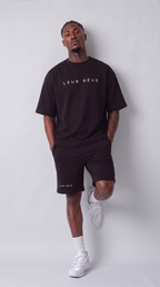 Man wearing the Leur Rêve Set in black, leaning back with one knee raised