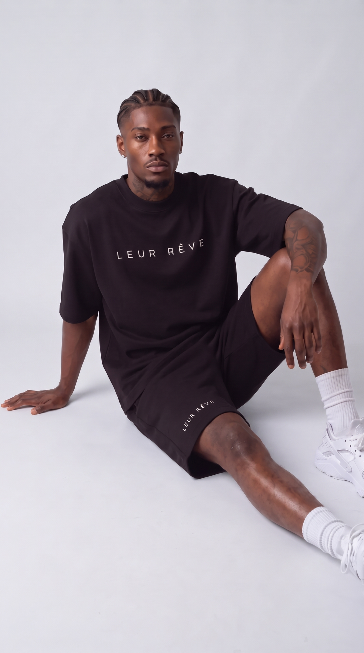 Man wearing the Leur Rêve Set in black, seated on the floor