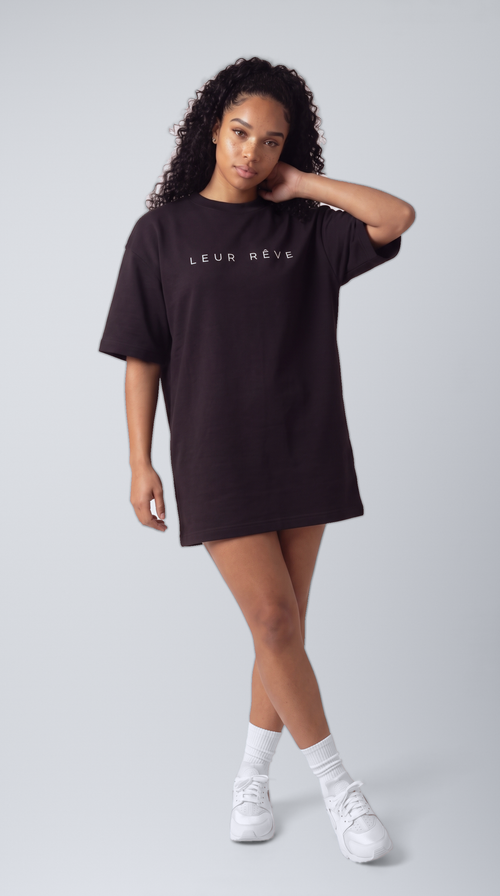 Woman wearing the Leur Rêve Tee in black, hand at neck