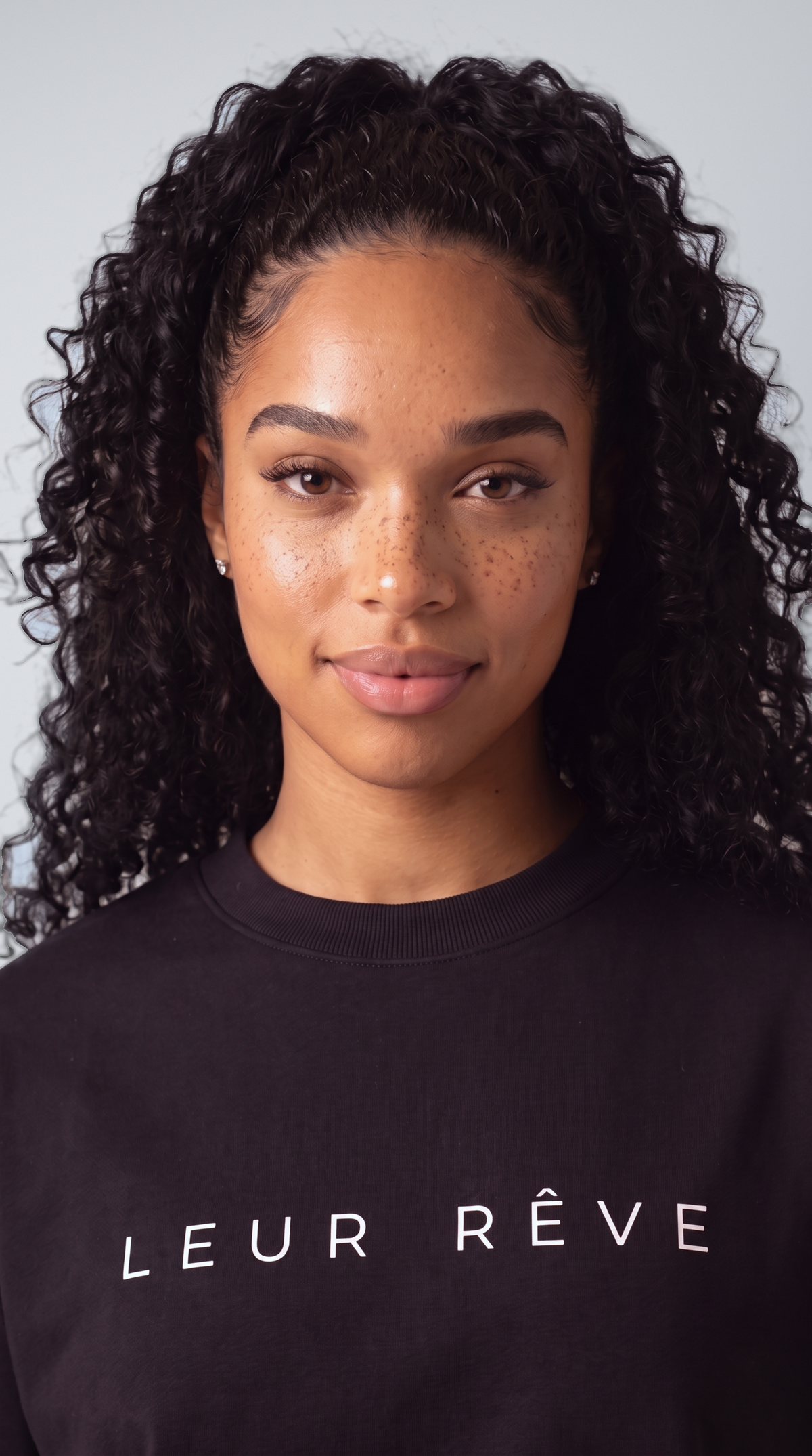 Close-up of a woman wearing the Leur Rêve Tee in black, wordmark across the chest